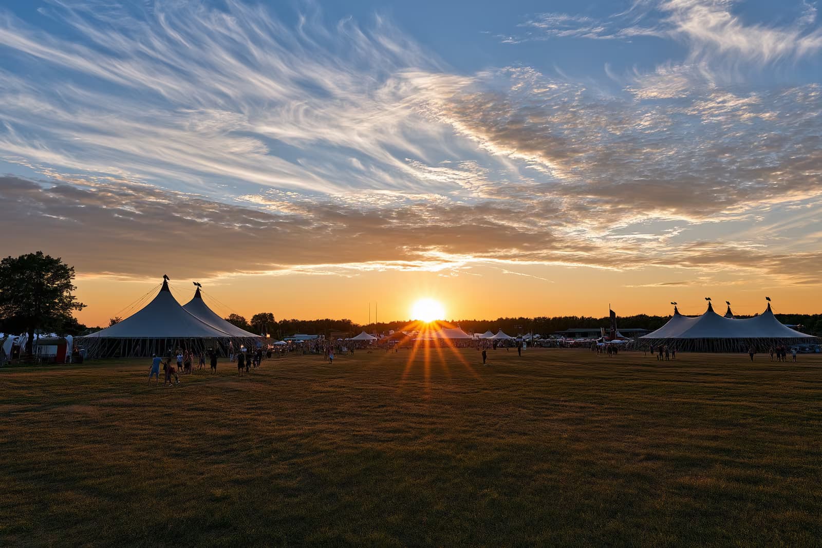 Big-top circus tents set up on an open field under a summer evening sky in Berlin.