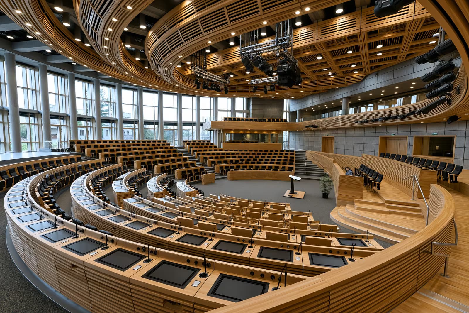 Wide interior of an empty national parliament plenary chamber before a debate.