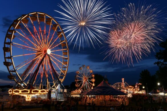 A brightly lit funfair with a large Ferris wheel and rides at dusk on the Heiligengeistfeld in Hamburg