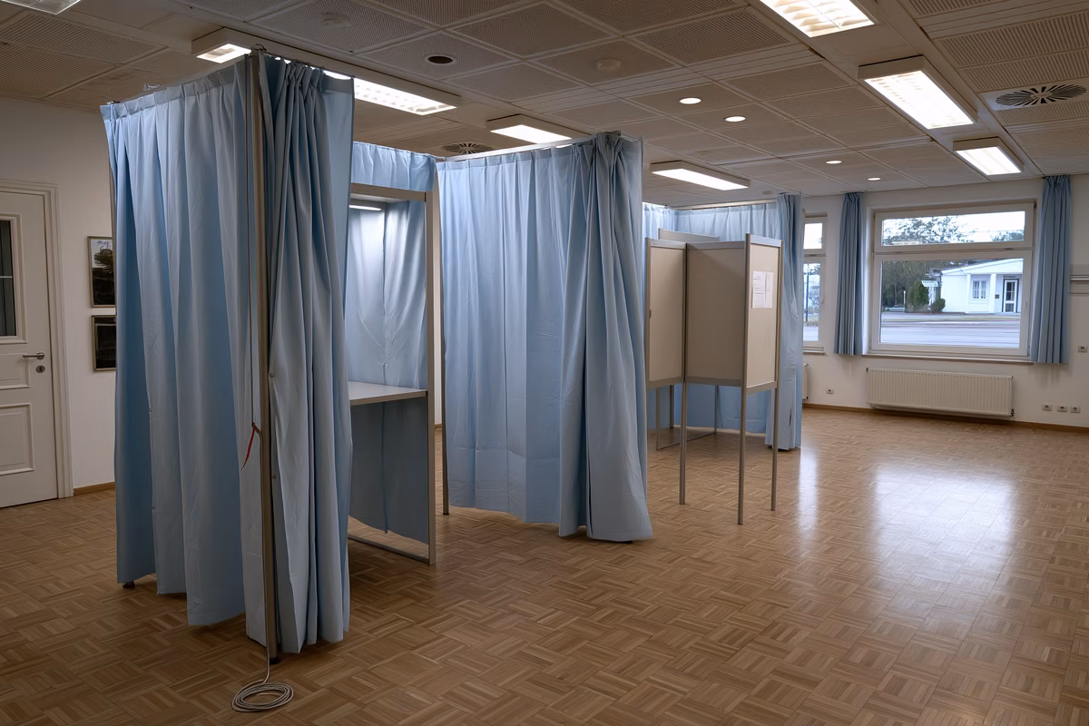 An empty voting booth with a pencil on a string in a German community hall